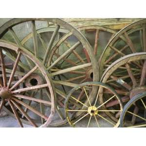  Antique Wooden Wagon Wheels Propped Against a Stucco Wall 
