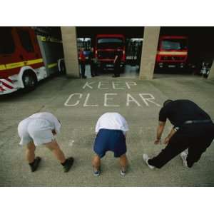  Fire Fighters Exercise and Stretch in Front of Their Station 